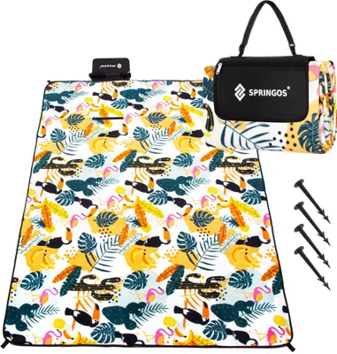 A folded picnic blanket with a tropical pattern and a carrying bag, along with ground stakes.