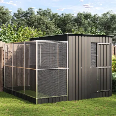 A metal and mesh aviary structure is set up in a grassy backyard with trees in the background.