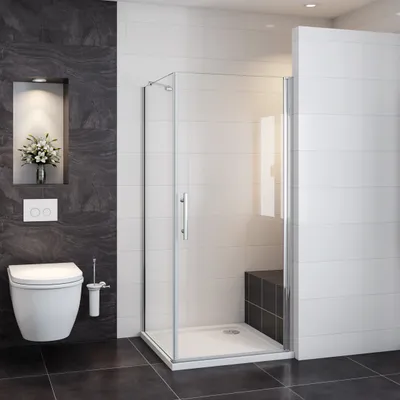 A modern bathroom with a toilet, shower cabin, and dark tiled walls.