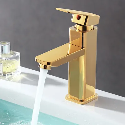 A gold faucet with water running into a sink, next to a bottle of perfume.