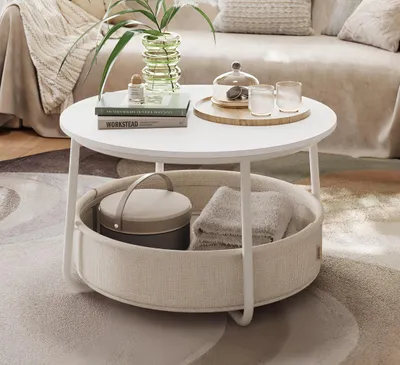 A round coffee table with a fabric basket underneath, placed in a living room setting.