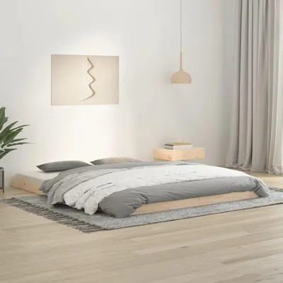 A bedroom scene with a low wooden bed frame, bedding, and a rug.