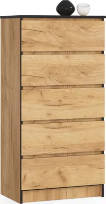A tall, narrow chest of drawers with a wood-grain finish and black accents, standing against a white background. Two decorative objects are placed on top.