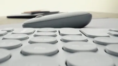 A close-up, low-angle shot of a keyboard with a mouse in the background.