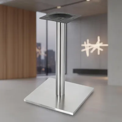 A stainless steel table base with a square top plate and a square base plate, shown in a modern interior setting.