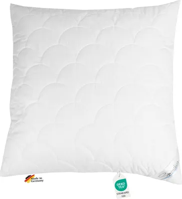 A white quilted pillow is shown against a white background. It has two tags attached to it.