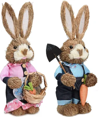 Two straw bunny figures dressed in clothing, one holding a basket with carrots, the other holding a shovel and a carrot.