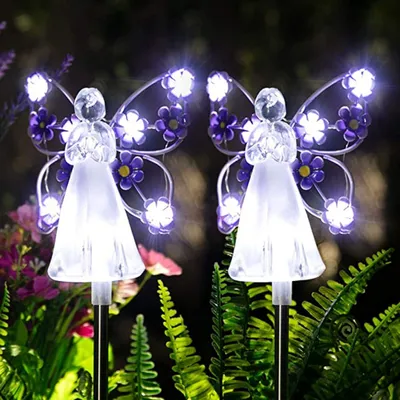 Two angel-shaped solar garden lights with purple butterfly wings are illuminated in a garden at night.