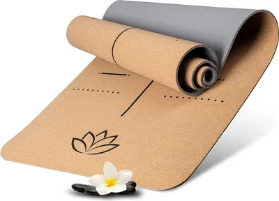 A rolled-up yoga mat with a lotus flower design and a small flower and stones in the foreground.
