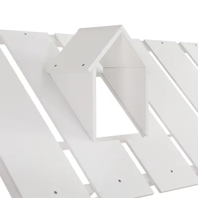 A close-up view of a white wooden bed frame with a house-shaped detail on top.