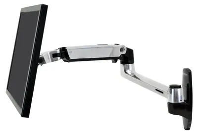 A monitor arm mounted to a wall with a monitor attached.