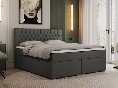 A dark gray boxspring bed with a tufted headboard is shown in a bedroom setting.
