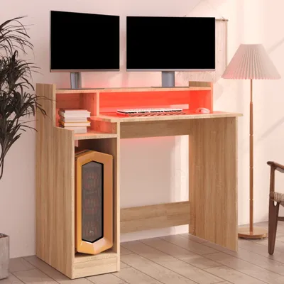 A modern computer desk with dual monitors, a keyboard, mouse, and a computer tower. The desk has built-in LED lighting.
