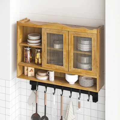 A wooden wall-mounted cabinet with sliding glass doors, filled with dishes and jars, hanging above a tiled wall with kitchen utensils below.