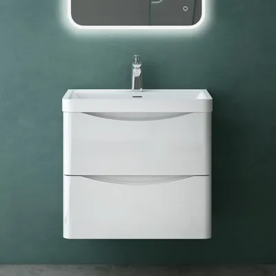A white vanity cabinet with two drawers and a sink is mounted on a teal wall. A modern faucet is installed in the sink, and a backlit mirror is mounted above it.