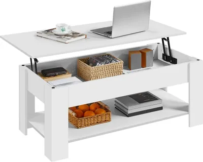 A white lift-top coffee table with storage compartments and shelves, displaying various items like a laptop, books, a basket of fruit, and decorative objects.