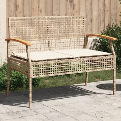 A beige poly rattan garden bench with acacia wood armrests and cushions, placed on a paved patio with grass and a wooden fence in the background.