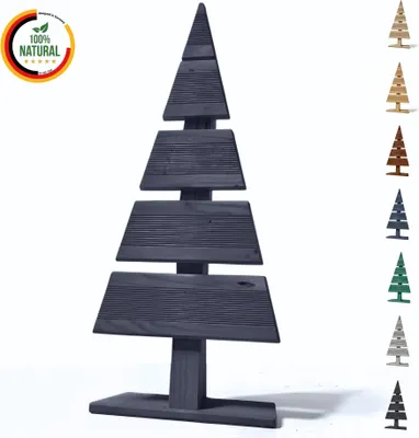 A dark gray wooden Christmas tree decoration stands on a white surface, with a row of smaller Christmas tree decorations in various colors lined up on the right side of the image.