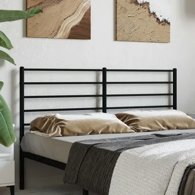 A close-up shot of a black metal bed frame headboard with pillows and blankets.