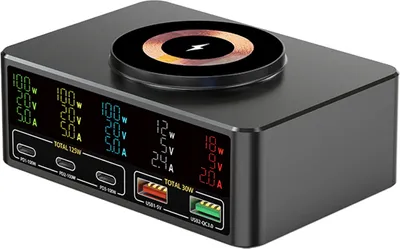 A black multi-port charging hub with a wireless charging pad on top, displayed on a white background. The front of the hub features multiple digital displays showing power output information for various ports.