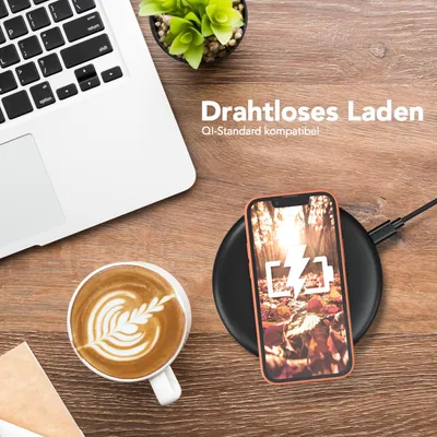 A desk setup with a laptop, coffee, and a smartphone charging wirelessly.
