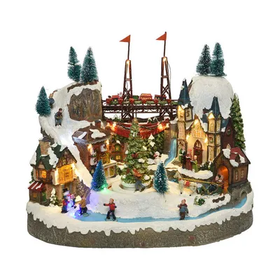 A miniature Christmas village scene with a train on a bridge, a church, houses, trees, and people ice skating.