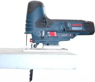 A Bosch jigsaw cutting into a piece of white material.