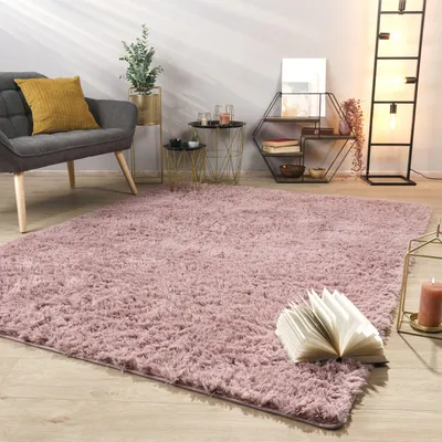A living room scene with a pink rug, a gray armchair, and decorative items.