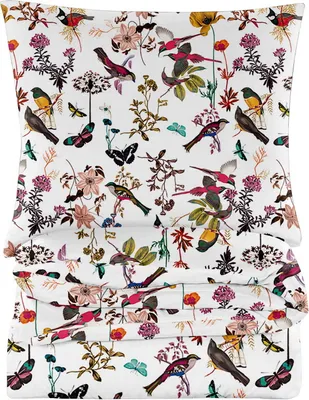 A stack of folded bedding with a floral and bird pattern.