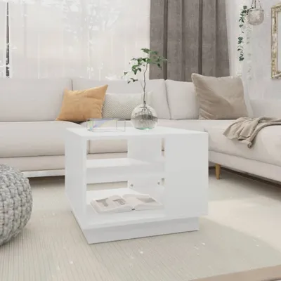 A white coffee table is placed in a living room setting with a sofa and decorative items.
