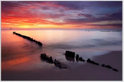 Produktbild von Wallario Wandbild Sandstrand im Sonnenuntergang - Roter Himmel, Größe: 61 x 91,50 cm, Poster mit weißem Aluminiumrahmen
