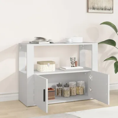 A white sideboard with two doors open, displaying jars and a basket inside. The sideboard is in a room with a plant and a framed picture on the wall.