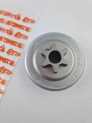 A close-up shot of a STIHL sprocket for a chainsaw, with packaging in the background.
