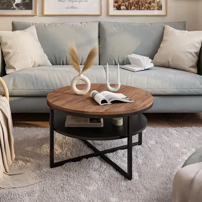 A round coffee table with a wooden top and black metal legs is placed on a fluffy rug in front of a light blue sofa. Decorative items are on the table and sofa.