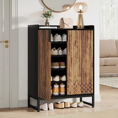 A shoe cabinet with shoes inside and on the floor in front of it, placed in a hallway next to a door.
