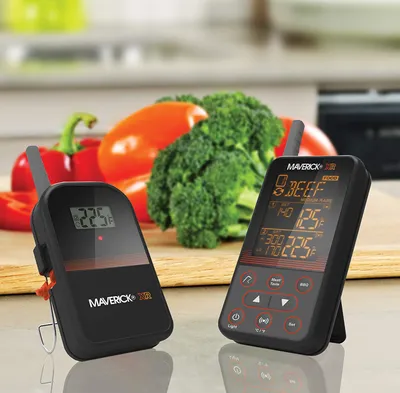 Two Maverick XR-40 wireless BBQ and meat thermometers are displayed on a countertop with fresh vegetables in the background.