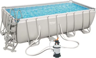 An above-ground rectangular swimming pool filled with blue water, with a ladder and a filter pump system.