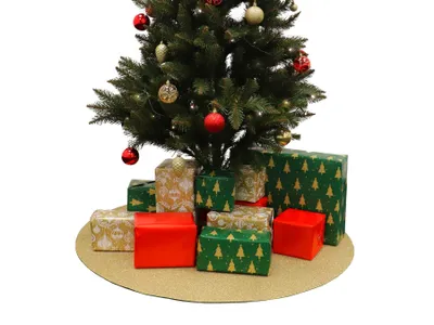 A Christmas tree with presents underneath, placed on a round gold mat.