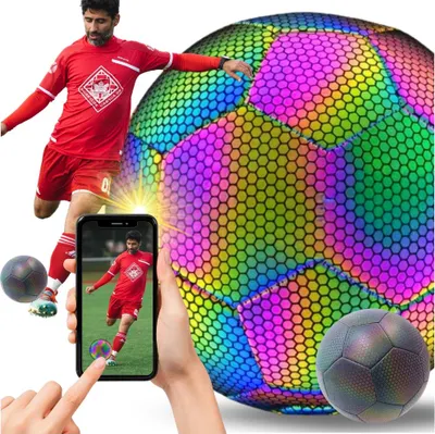 A soccer player in a red uniform kicks a large, iridescent soccer ball. A smartphone displays a smaller image of the same soccer player kicking a ball.