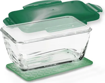 A clear glass food container with a green lid and a green mat underneath.