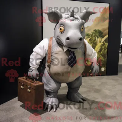 Immagine prodotto di Personaggio mascotte REDBROKOLY di un triceratopo grigio vestito con camicia Oxford e valigetta
