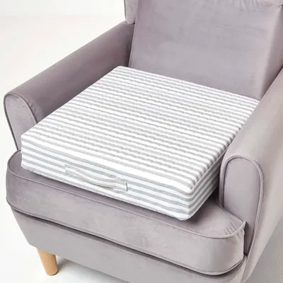 A striped cushion is placed on a gray armchair.