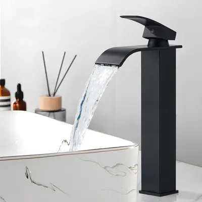 A modern black waterfall faucet is shown in use over a decorative sink.