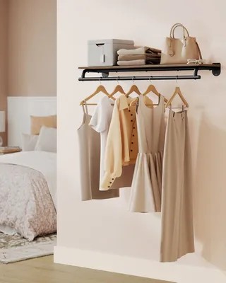 A bedroom scene with a wall-mounted wardrobe rack holding clothes and a shelf above with accessories.