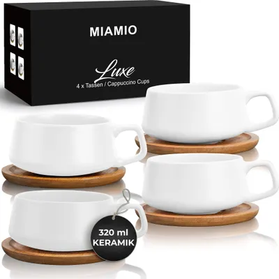 A set of four white ceramic cappuccino cups with wooden saucers, displayed with their packaging in the background.