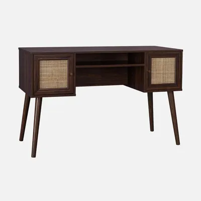 A dark wood desk with rattan accents and angled legs, presented against a plain light gray background.