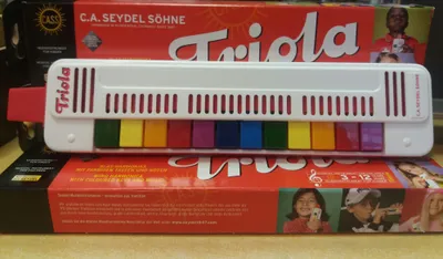A Seydel Triola 12 harmonica is placed on top of its packaging.