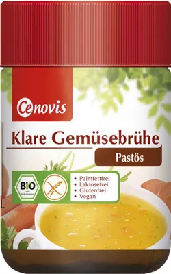 A jar of vegetable broth paste with a bowl of soup in the foreground.