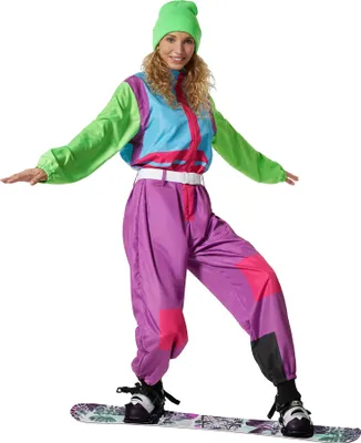 A woman wearing a retro ski suit and beanie, standing on a snowboard.