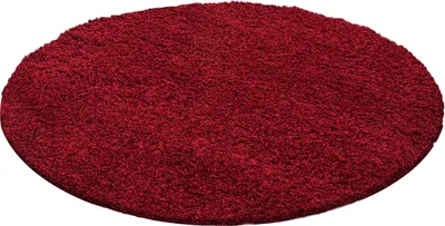 A round, red, high-pile rug is shown from a slightly elevated angle against a white background.
